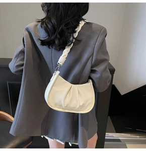 Detail of cream pleated hobo bag with a thick braided strap on a model's shoulder