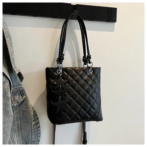 Détail du sac bandoulière matelassé noir avec motif losanges et breloques étoiles