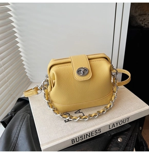 Close-up of yellow lychee leather handbag with silver chain strap and metallic twist lock