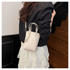 Détail du mini sac blanc cassé avec texture litchi et breloque en forme de cœur argenté