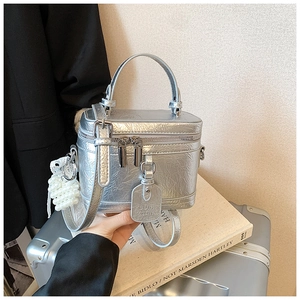 Silver metallic mini box bag with textured folds, pearl charm, and adjustable shoulder strap