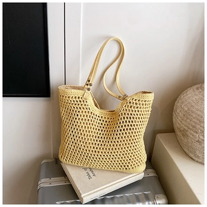 Macro view of woven yellow tote bag with textured cutout pattern and leather handles