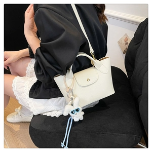 Detail of white lychee leather tote bag with gold buckle and cute plush bunny charm