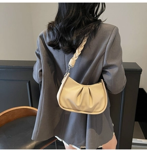 Detailed view of beige cloud bag featuring a chunky woven shoulder strap and textured leather