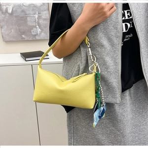 Dettaglio della borsa a spalla in pelle gialla con moschettone e ciondolo delfino