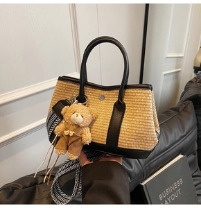 Détail du sac cabas en paille avec garniture en similicuir noir et accessoire d'ours en peluche