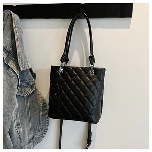 Détail du sac seau matelassé noir avec breloques étoiles et bandoulière amovible