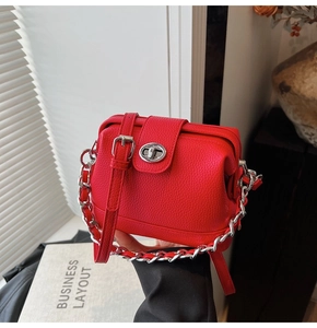 Close-up of red pebbled leather handbag with silver twist lock and dual strap detail