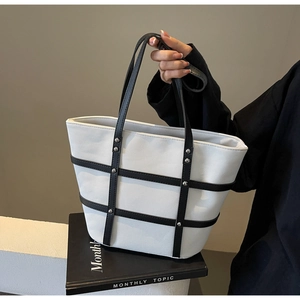 Detail of vintage canvas tote bag with black leather trim and silver metal studs