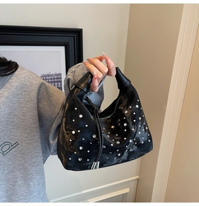Detailed macro view of black glossy hobo bag featuring sparkling scattered rhinestones
