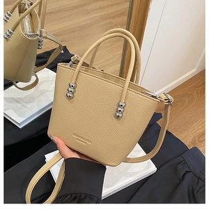 Detail of beige leather crossbody bag with silver bead hardware and textured finish