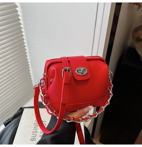 Detail of red lychee leather handbag featuring a silver twist lock and chunky chain