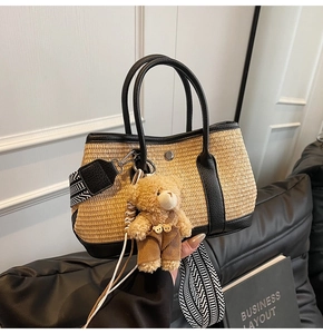 Détail du sac seau en paille avec garniture en cuir noir et bandoulière rayée