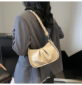 Detail of cream pleated cloud bag with textured leather and woven handle strap