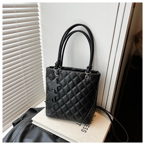 Détail du sac cabas matelassé noir avec lanières en cuir et breloques étoiles