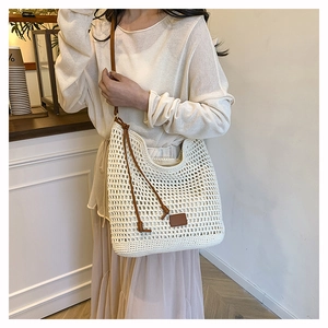 Detail of woven straw tote bag with leather straps on model in bohemian style