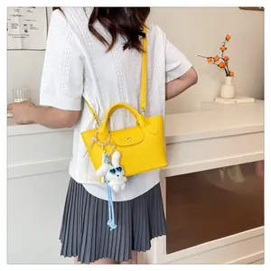 Bright yellow mini tote bag with plush rabbit charm worn by a model in a modern room