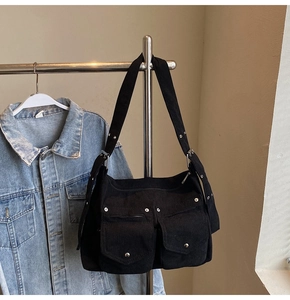 Détail du cabas en velours côtelé noir avec poches à rabat et rivets métalliques