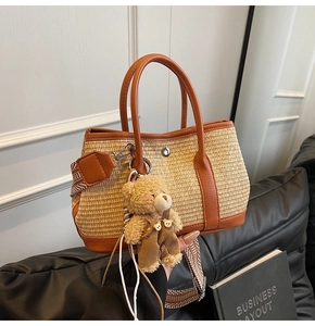 Détail d'un sac en paille tressée avec finitions cuir, breloque ours et bandoulière