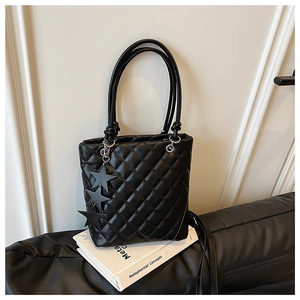 Détail d'un sac seau matelassé noir avec poignées en corde et breloques étoiles