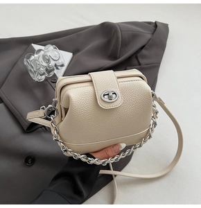 Close-up of cream pebble leather texture and silver twist lock on chain crossbody bag