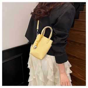 Détail du mini sac jaune en cuir grainé avec breloque cœur et bandoulière amovible