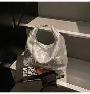 Detail of silver metallic handbag with crystal rhinestones and metal handle on stairs