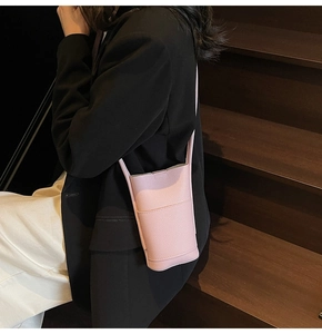Detail of pink pebbled leather crossbody phone bag with front pocket and slim strap