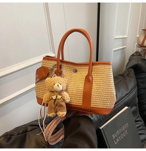 Détail du sac seau en paille tressée avec bordure en cuir orange et breloque ours