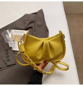 Detail showing bright yellow leather cloud bag with braided strap and pleated texture