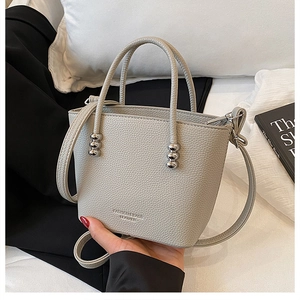 Detail of grey bucket bag showing litchi grain leather and silver beaded handle decor