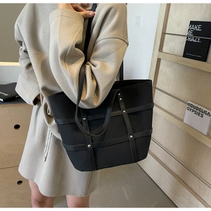 Macro detail of black matte tote bag featuring silver rivet accents and strap texture