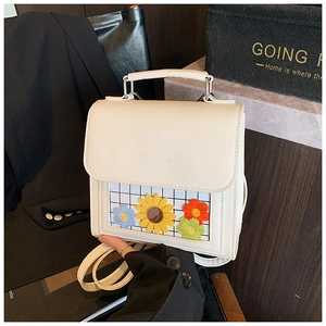 Detailed shot of white leather handbag with grid window and vibrant flower embroidery