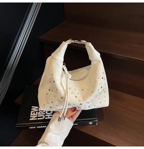 Detail view of white pleated dumpling bag with sparkling rhinestones and metal handle