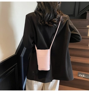 Close-up of a light pink lychee grain leather crossbody phone bag on a model