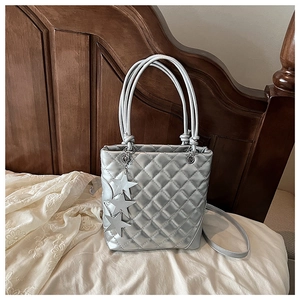 Détail d'un sac à main matelassé argenté avec finition métal et breloques étoiles