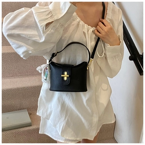 Detail of black lychee grain bucket bag with gold hardware and lace bow accessory