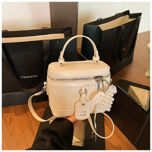 Close-up of cream mini vanity bag with elegant pearl and lace bow charm details