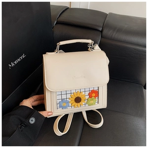 Detail of off-white backpack with transparent pocket featuring colorful knitted flowers