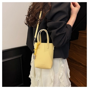 Détail du mini sac cabas jaune texture litchi avec breloque noeud tissé et bandoulière