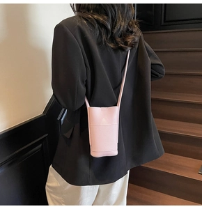 Detail of light pink lychee pattern crossbody phone bag on model in black blazer
