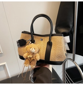Détail du sac seau en paille avec anses en cuir noir et petit ours en peluche