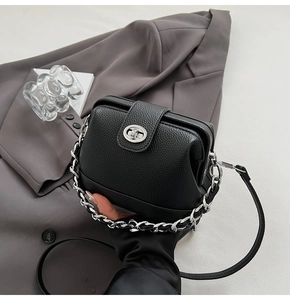Detail of black lychee grain leather handbag with silver chain and twist lock clasp