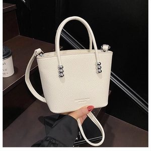 Close-up of cream white lychee leather texture and silver metallic ball details on bucket bag