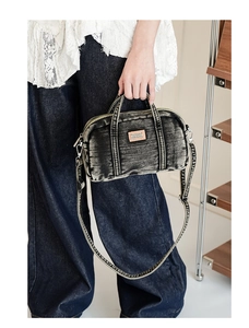 Gros plan détaillé du sac en denim délavé gris foncé avec patch logo en cuir orange