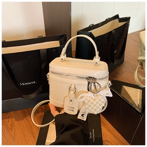 Detail of white patent leather box bag with pearl heart charm and lace bow decor
