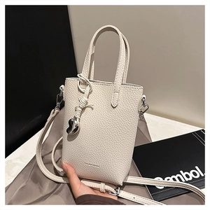 Détail du mini sac à téléphone en cuir blanc cassé avec pendentif cœur et bandoulière