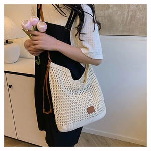 Detail of cream woven tote bag featuring hollow crochet texture and brown leather patch