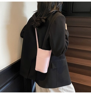 Pink lychee texture crossbody phone bag styled with a black blazer on indoor stairs