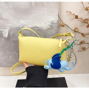 Dettaglio borsa in pelle gialla con ciondolo elefante blu e catena di perline a cuore